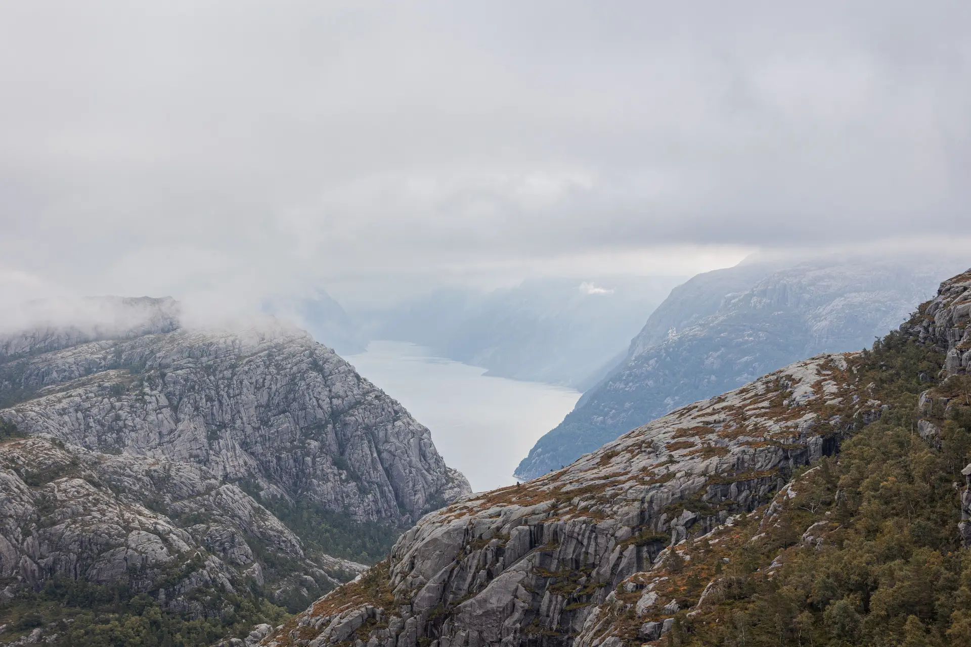 Tåkete norsk fjord omgitt av majestetiske fjelltopper