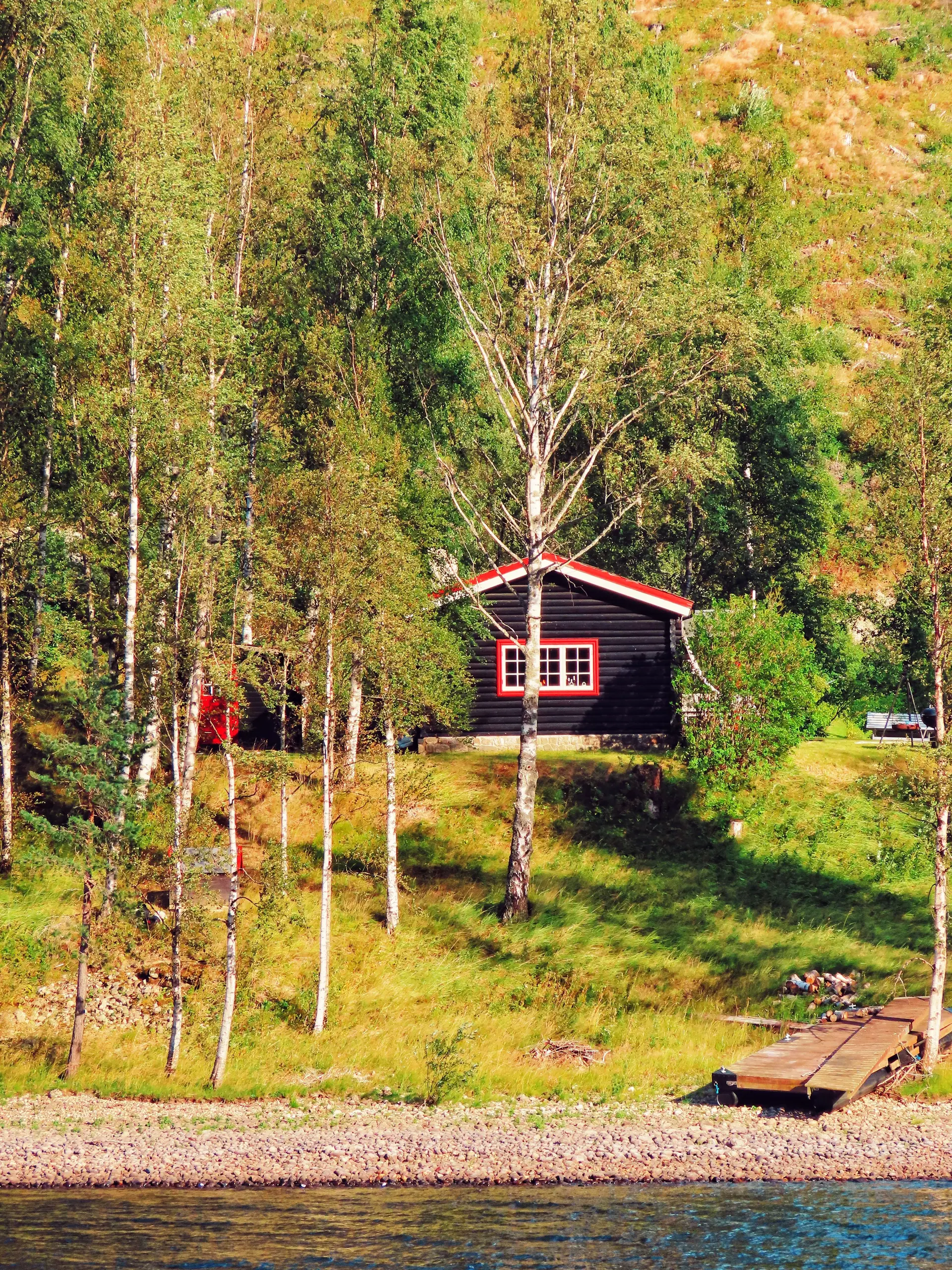 Norsk trehytte ved en fredfull innsjø om sommeren